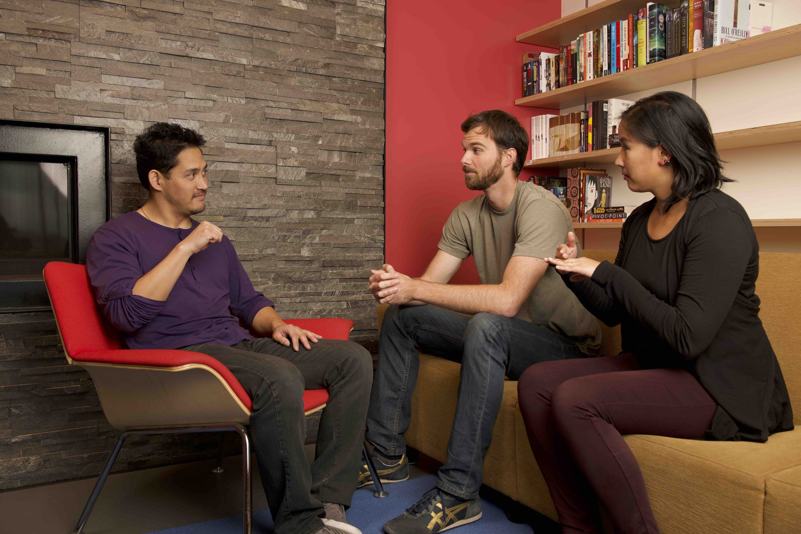 Two men and a woman having a conversation; one of the men and the woman are using sign language.